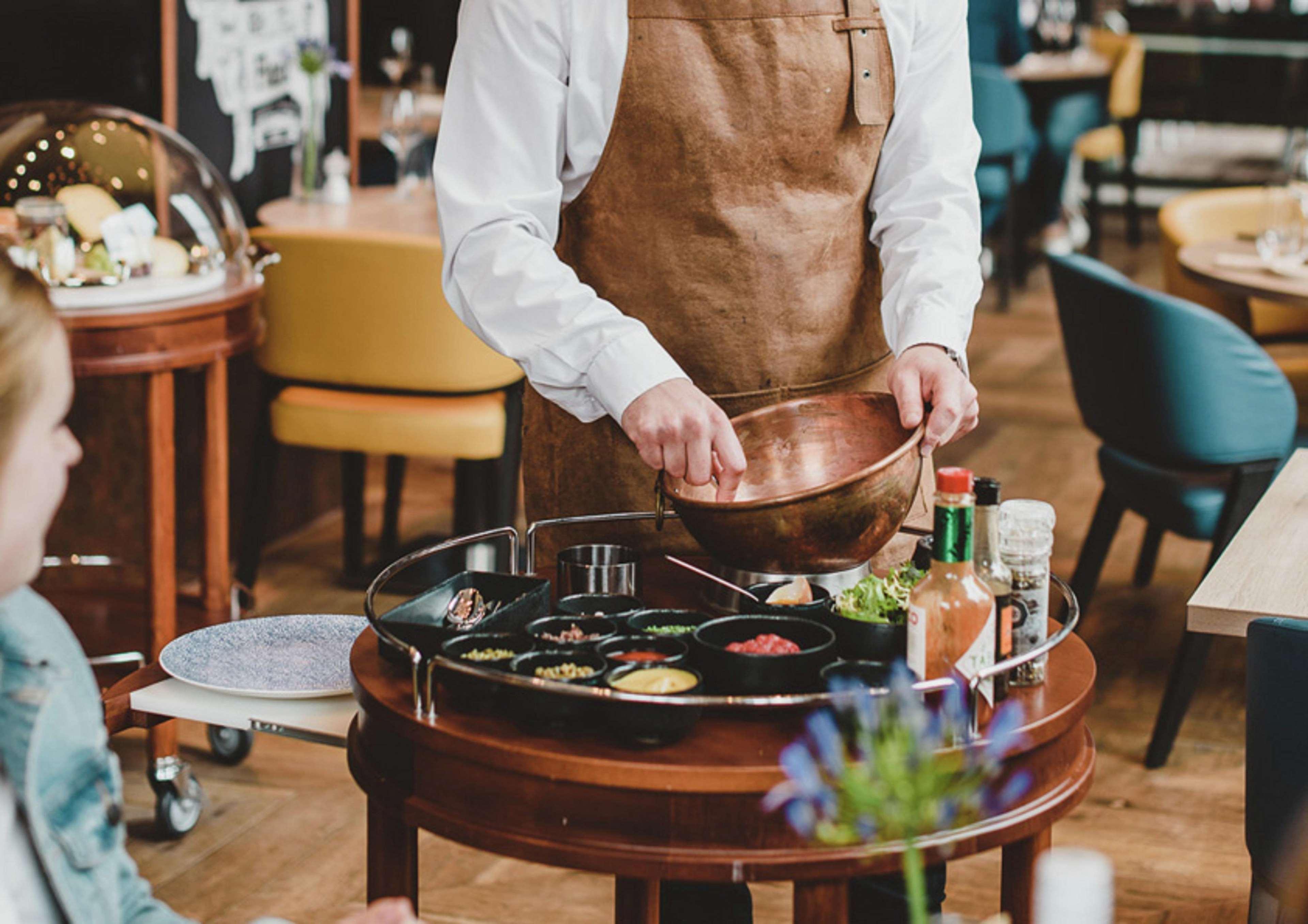 힐튼 더 헤이그 외부 사진 A server prepares a dish at a restaurant